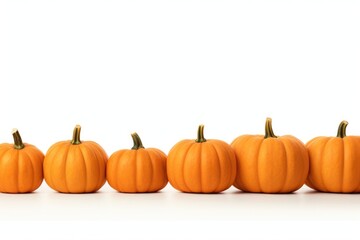 A row of small orange pumpkins on a white surface. Ideal for autumn and Halloween-themed designs.
