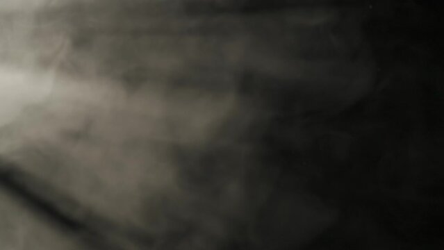 Cloud of dense gray smoke with dust particles in spotlight on black background. Texture and abstract art. HDR BT2020 HLG Material.