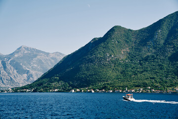 Motor boat sails on the sea along a mountain ridge