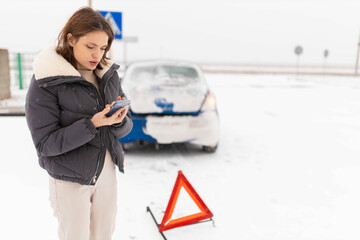  young female driver who crashed her car on a slippery winter road in the snow calls a tow truck...
