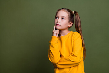 Portrait of minded puzzled small kid with tails dressed yellow sweatshirt look at offer empty space...