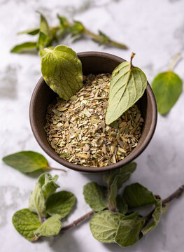 Chopped dried oregano put in a ceramic bowl and fresh oregano leaves on the ceramic plate