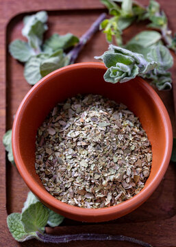 Chopped dried oregano put in a ceramic bowl and fresh oregano leaves on the ceramic plate