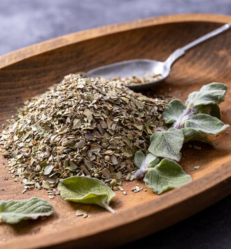 Chopped dried oregano and fresh oregano leaves on a wooden board