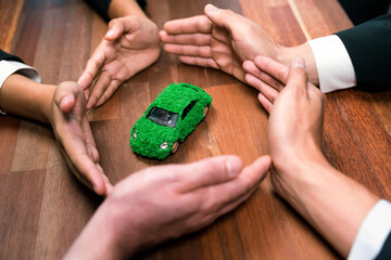Business people holding EV car model as business synergy partnership unite and take action to...
