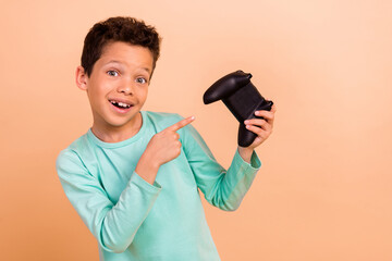 Photo of glad cheerful boy wear trendy turquoise clothes recommend buy playstation isolated on beige color background