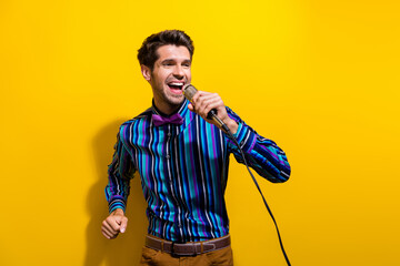 Portrait of cheerful guy dressed stylish shirt singing pop song in microphone at retro party...