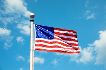 Fototapeta premium USA (United States of America) Flag on the flag pole waving beautifullyin the sky.