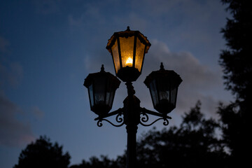 silhouette of an old fashioned standing lamp lit orange against a dark night sky