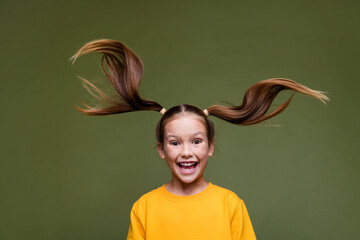 Portrait of impressed overjoyed small kid with fluttering hair dressed yellow sweatshirt staring...