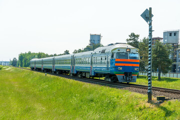Naklejka premium The locomotive is moving by rail. A passenger train goes to the railway station, transporting people and various goods by rail.