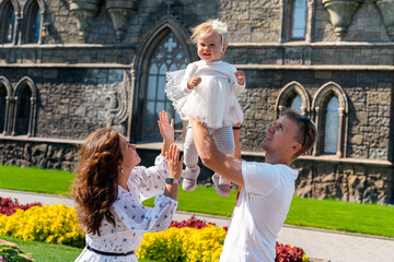 A young family mother father and child in a dress laughing against the background of a flower...