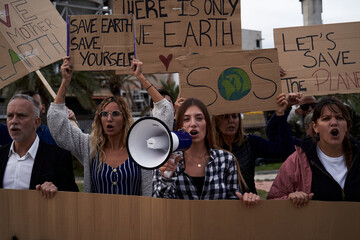 Group of people from different ages and nationalities gathered to protest against factories and...