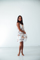 Brunette in floral dress posing on white background