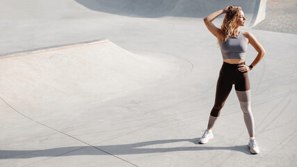 Healthy young sportive woman warming up, stretching before outdoor workout - obrazy, fototapety, plakaty