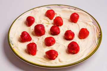 Fresh juicy strawberries in whipped cream in a plate on the table.
