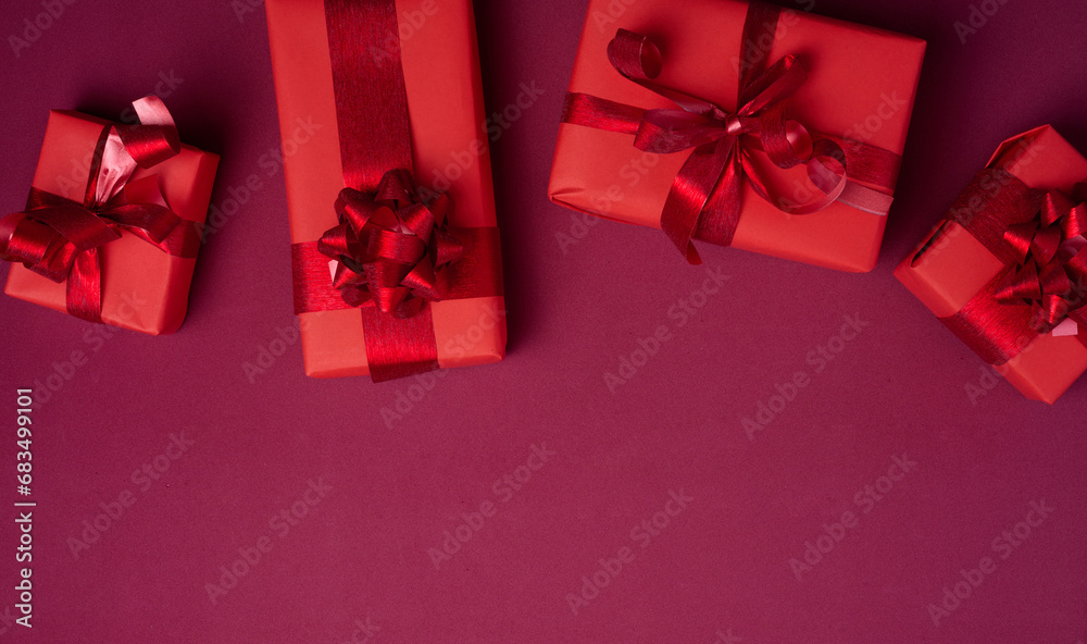 Wall mural Boxes packed in red paper and tied with ribbon on a red background, gifts