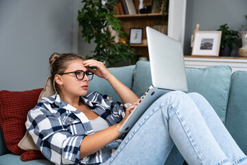 Confused young woman looking on laptop at home feeling bewildered by no connection, reading online news in internet, annoyed teen girl angry with stuck computer problem, scam spam email, system error