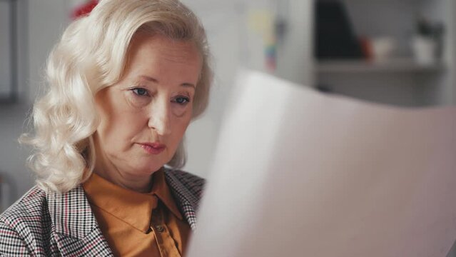 Close-up of woman property developer examining building blueprint in her office