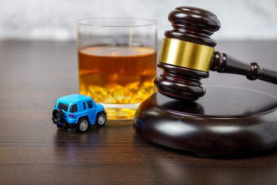 Judge's mace on a table in a court of law, glass of whiskey and miniature car. No drinking while driving concept