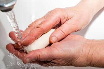 An elderly man washes his hands with soap, wrinkles, old.
