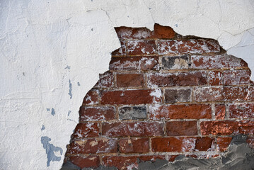 The texture of an old brick wall with broken white plaster.