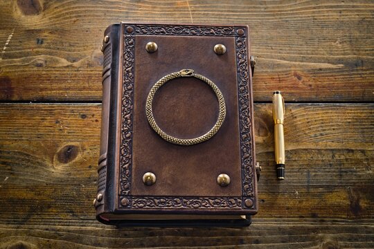 Brown leather book with carved Ouroboros symbol 