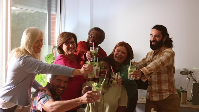 group of friends of different generations, multiracial, diverse, celebrating party at home with mojitos - family and friendship concept -