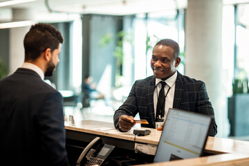 Businessman paying stay at hotel with credit card at reception