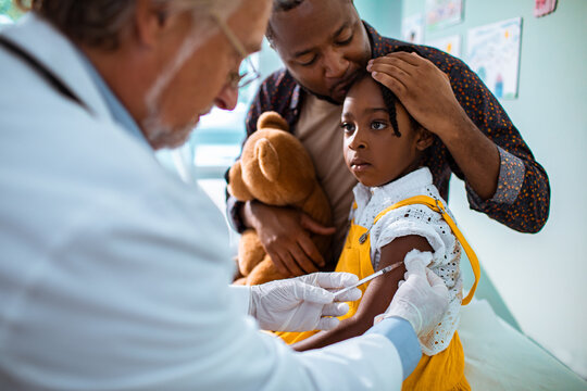 Doctor vaccinating little girl patient at clinic