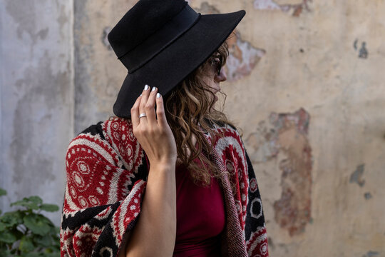 Young Latin American woman with curly hair, hat, sunglasses and red clothes.