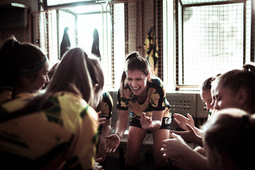 Female soccer players huddle together in unity in the locker room