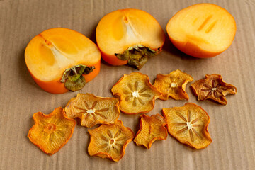 Persimmon chips on craft paper next to ripe orange persimmons.