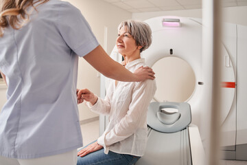 Cropped view of the female doctor calming senior patient woman before the MRI scanning - 683514364