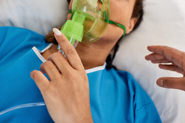 cropped view of doctor comforting ill african american woman lying in hospital bed with oxygen mask