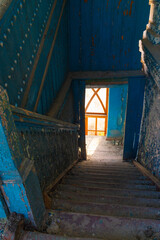 Old abandoned dirty wooden staircase in empty building with blue wooden walls