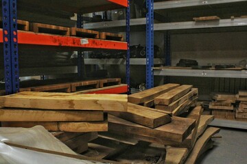 Close-up of wooden planks at lumber warehouse. Storage shelves with panel in lumberyard. Background of boards on shop. Processed timber blocks products in market. Raw wood drying in carpenter workshop