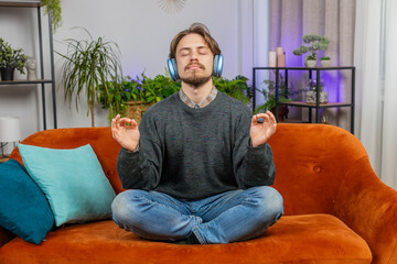 Keep calm down, relax. Bearded young man listening music breathes deeply, eyes closed meditating...