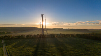 Windmills at Sunrise Amidst Misty Fields