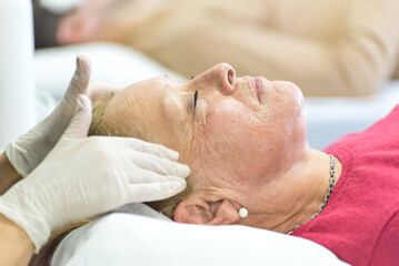 Obraz na płótnie Canvas esthetician performing facial massages to an elderly woman, relaxing, facial treatment