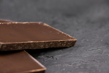 Dark chocolate on a dark background. Bar of dark chocolate. Chocolate pieces