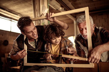 Young Boy Learns Woodworking Skills from His Elderly Grandfather and Father in a Workshop