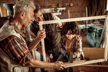 Young Boy Learns Woodworking Skills from His Elderly Grandfather and Father in a Workshop
