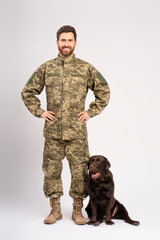 Handsome smiling bearded man, soldier training brown Labrador dog isolated on white background