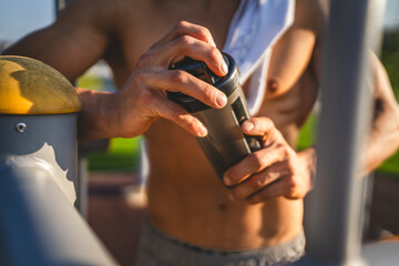 One caucasian man young male athlete take a brake during outdoor training in the park outdoor gym hold supplement shaker in hand happy confident strong copy space - Powered by Adobe