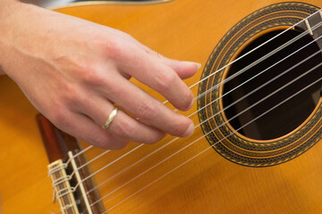 Fototapeta premium Female human hand playing an accoustic guitar strumming the strings
