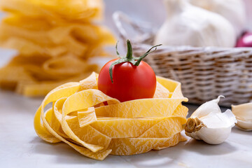 Pasta tagliatelle with tomatoes and garlic in a basket of noodles