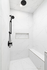 A luxury shower with white marble walls and floor, a black faucet and showerhead, and a marble niche shelf. - obrazy, fototapety, plakaty