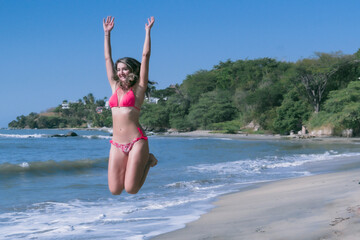 Capturing the magical moment of a radiant young woman, enthusiastically leaping on the golden sands of a Caribbean beach, her bronzed and slender body personifies the vibrant joy of the paradise 