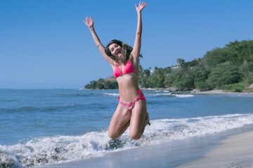 With a radiant aura, the bikini-clad woman runs towards freedom on the warm Caribbean beach, her...